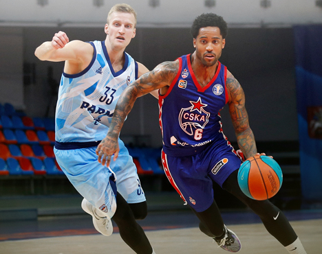 На изображении два баскетболиста в игровом моменте. Игрок в форме сине-голубого цвета пытается защититься, а спортсмен в форме ЦСКА с мячом атакует. Сцена происходит на баскетбольной площадке